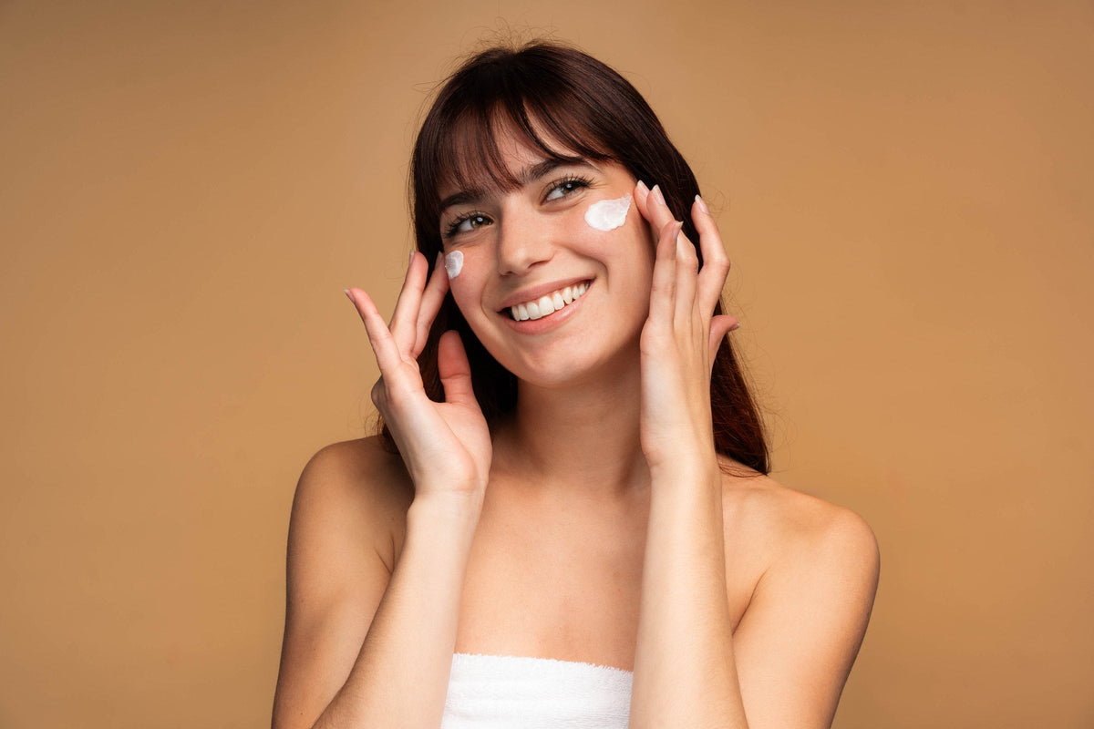A young woman smoothing cream onto her cheek