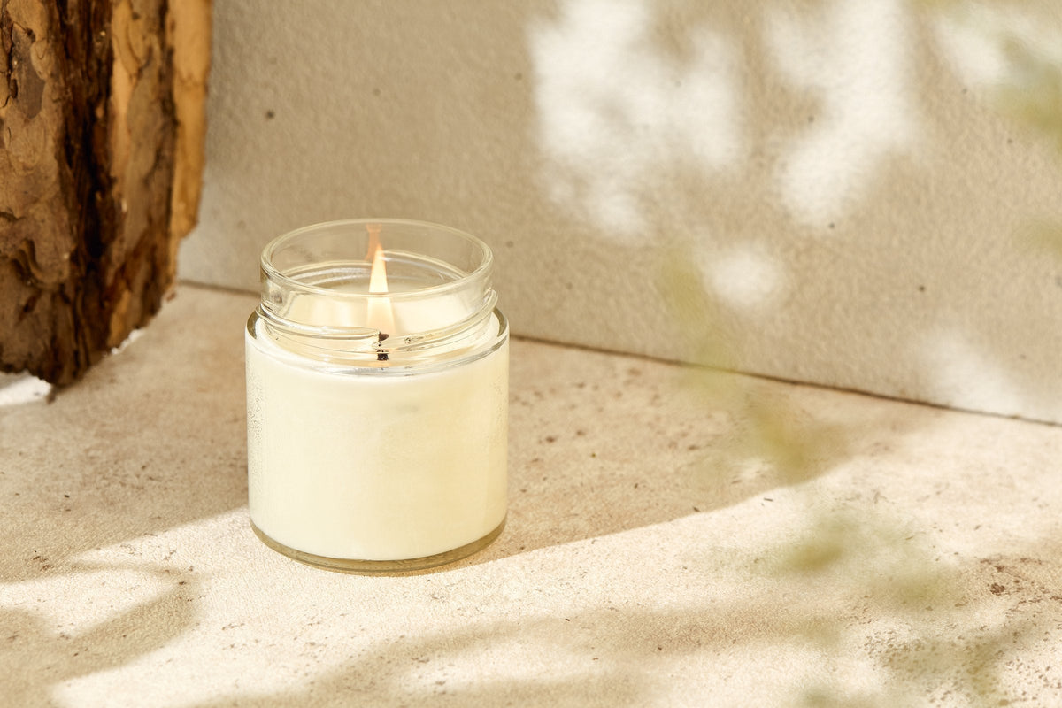 A lit scented candle in a glass jar