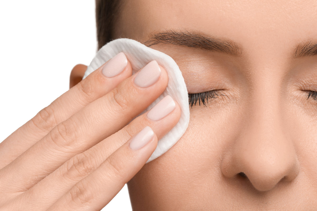 A cotton pad held gently against a closed eye to remove make-up