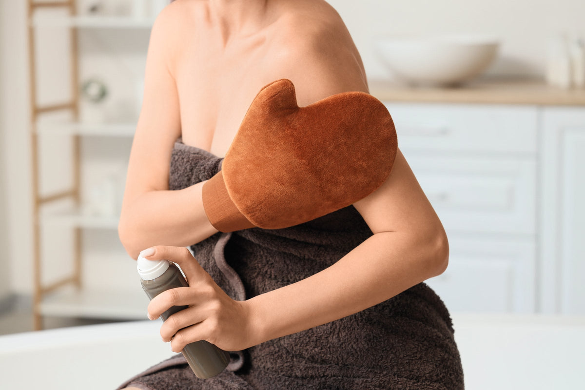 A woman applying self-tanning mousse with a mitt