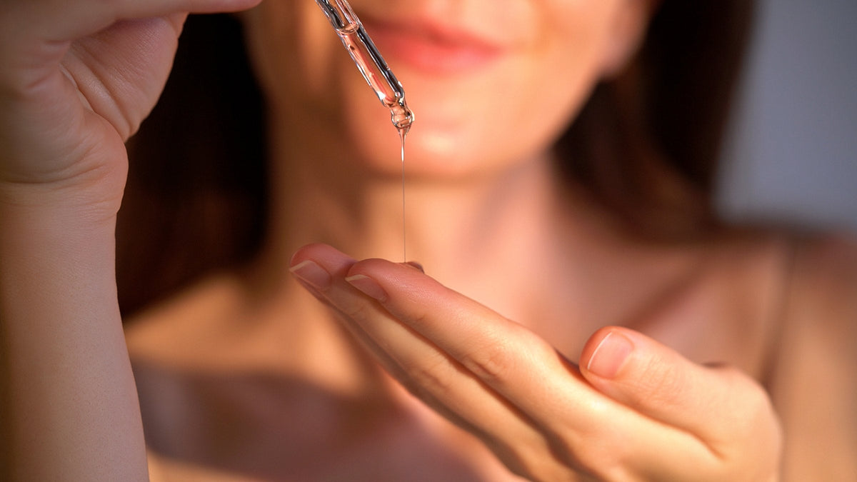 A woman holding a serum dropper, a drop falling into her palm