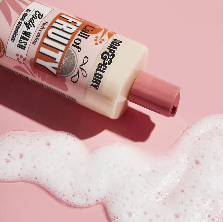 Soap &amp; Glory Plastic cylindrical body wash bottle in pink, orange and beige with flip-top cap, fruit and floral graphics, bold text branding, measurement markings — .