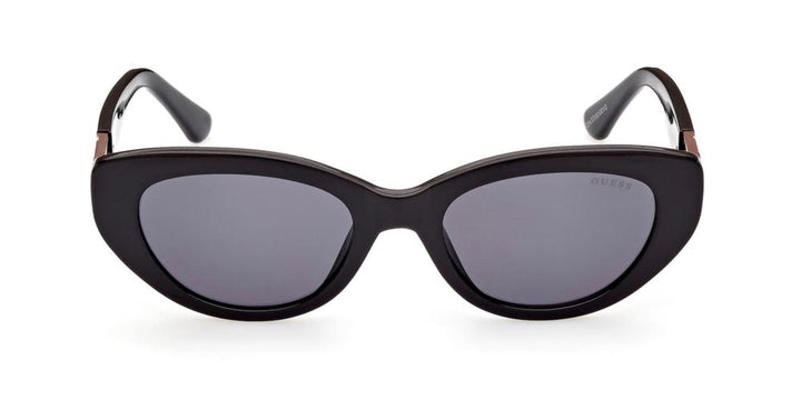 Black cat-eye sunglasses with gold logo accents on temples and dark tinted lenses on white background
