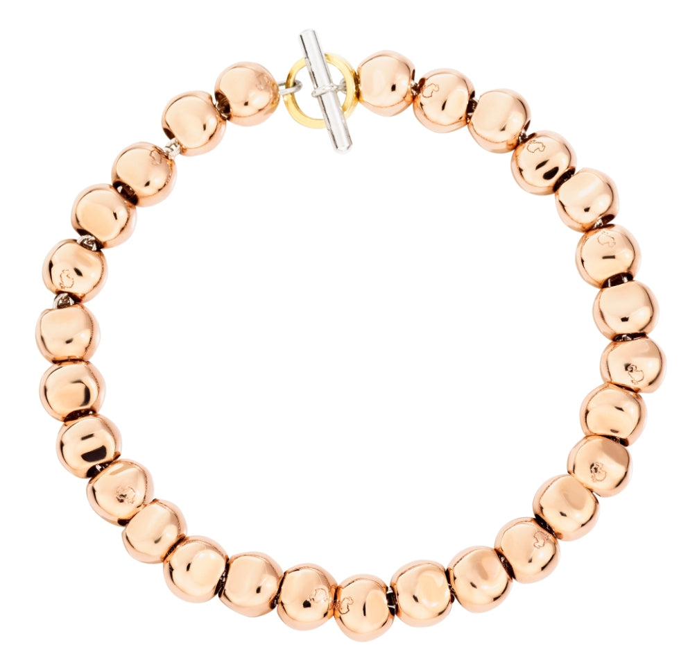 Rose gold beaded bracelet with polished round beads and silver toggle clasp on neutral background